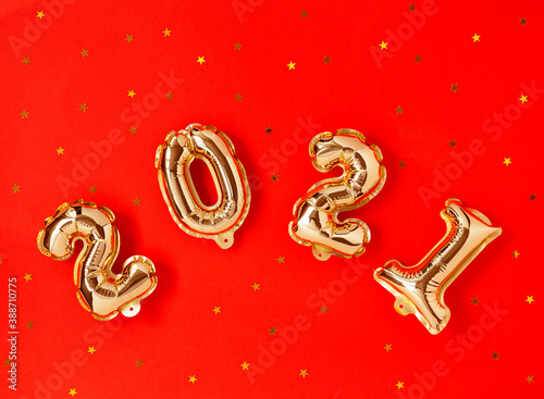 Happy New year 2021 celebration. Gold and foil balloons numeral 2021 and stars on red background. Flat lay © Elena Verba