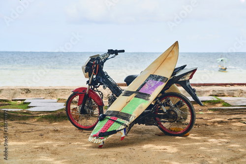 Photography Short surf board leaning in a motorcycle with the seaside as background