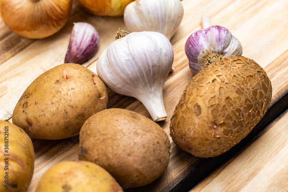Potatoes and two heads of garlic on a wooden background. Potatoes and two heads of garlic on a wooden background.