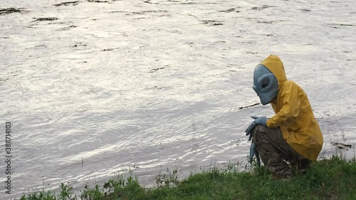 alien stands by river in yellow raincoat,looks around, UFO concept, science Fiction.alien has arrived on earth.actor in alien costume