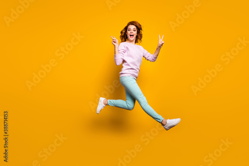 Full body photo of cheerful crazy excited woman enjoy spring vacation holiday jump make v-sign scream rejoice wear casual style clothes isolated over yellow color background