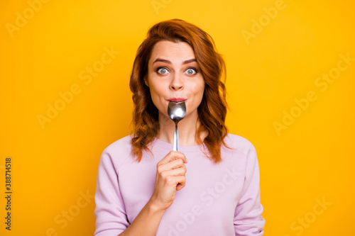 Portrait of astonished inspired girl have weekend in restaurant taste dish enjoy lick spoon impressed stare stupor wear pink jumper isolated over yellow color background photo
