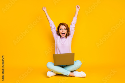 Full length photo of delighted crazy woman sit floor legs crossed folded work laptop win lottery raise fists scream yeah wear pink teal trousers sneakers isolated over bright color background © deagreez