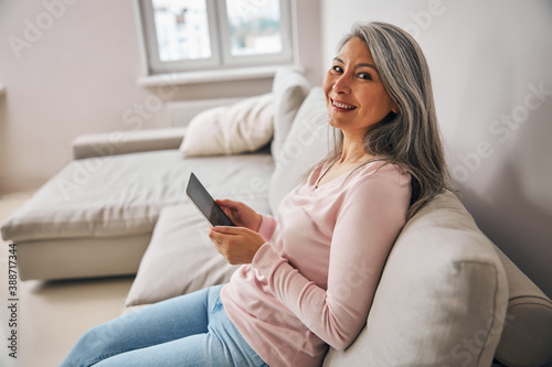 Charming elegant female with technology device in hands at home