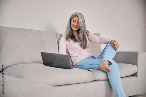 Beautiful woman freelancer looking to the screen her computer while surfing internet at home