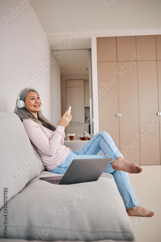 Charming female laughing while listening something in the home