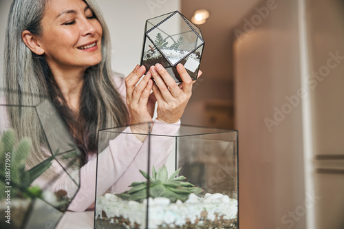 Cheerful woman holding geometric glass succulent terrarium