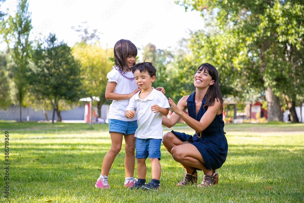Two happy kids and their mom playing active games in park. Boy with closed eyes walking on grass lead by sister and mother. Family outdoor activity and leisure concept Two happy kids and their mom playing active games in park. Boy with closed eyes walking on grass lead by sister and mother. Family outdoor activity and leisure concept