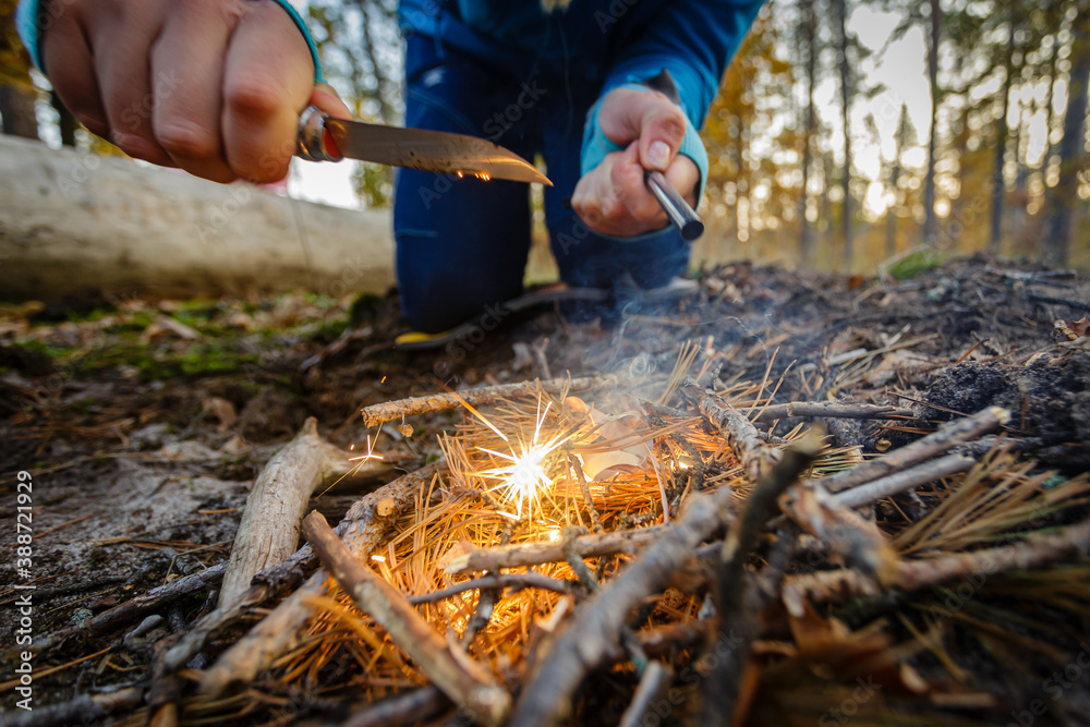 Obraz premium Man outdoors makeing fire by flint. View from above. Flying sparks.