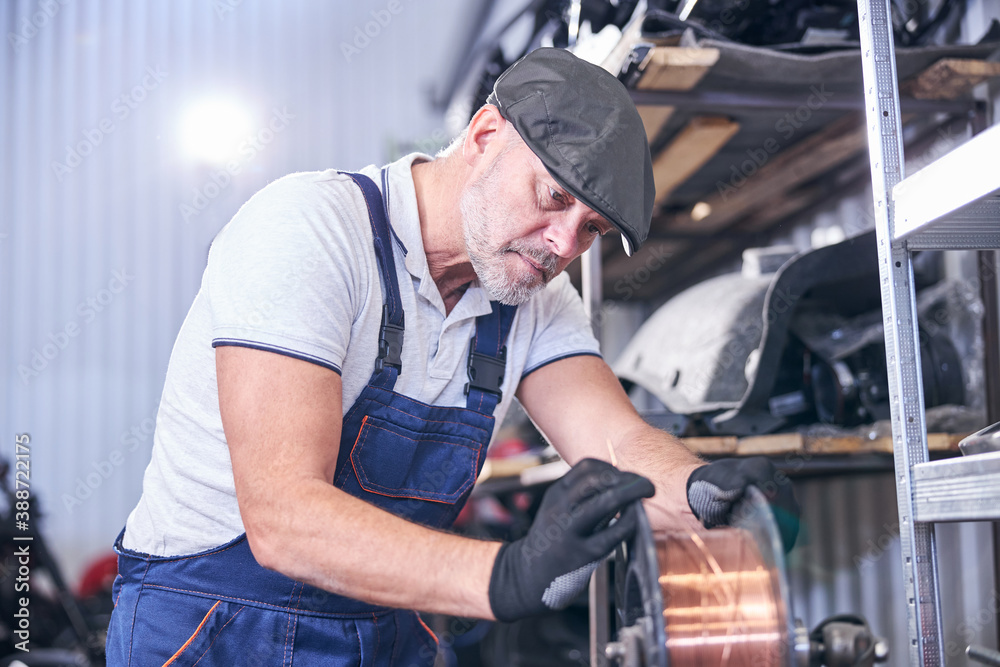 Bearded mechanic using copper wire at repair service station