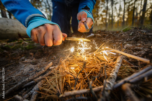 Man outdoors makeing fire by flint. View from above. Flying sparks.