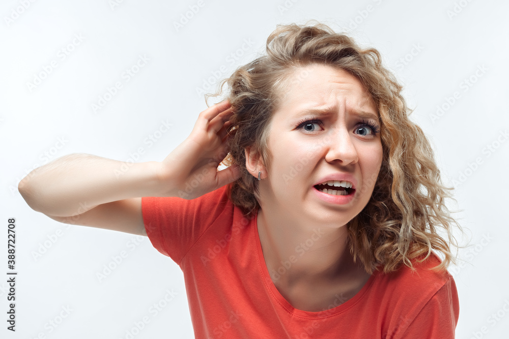 Image of pretty blonde girl holding hand near ear trying to listen something. Human emotions, facial expression concept Image of pretty blonde girl holding hand near ear trying to listen something. Human emotions, facial expression concept
