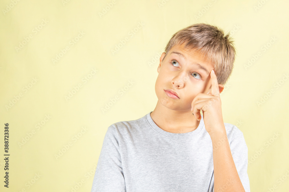 Thinking young boy standing over light yellow background Thinking young boy standing over light yellow background