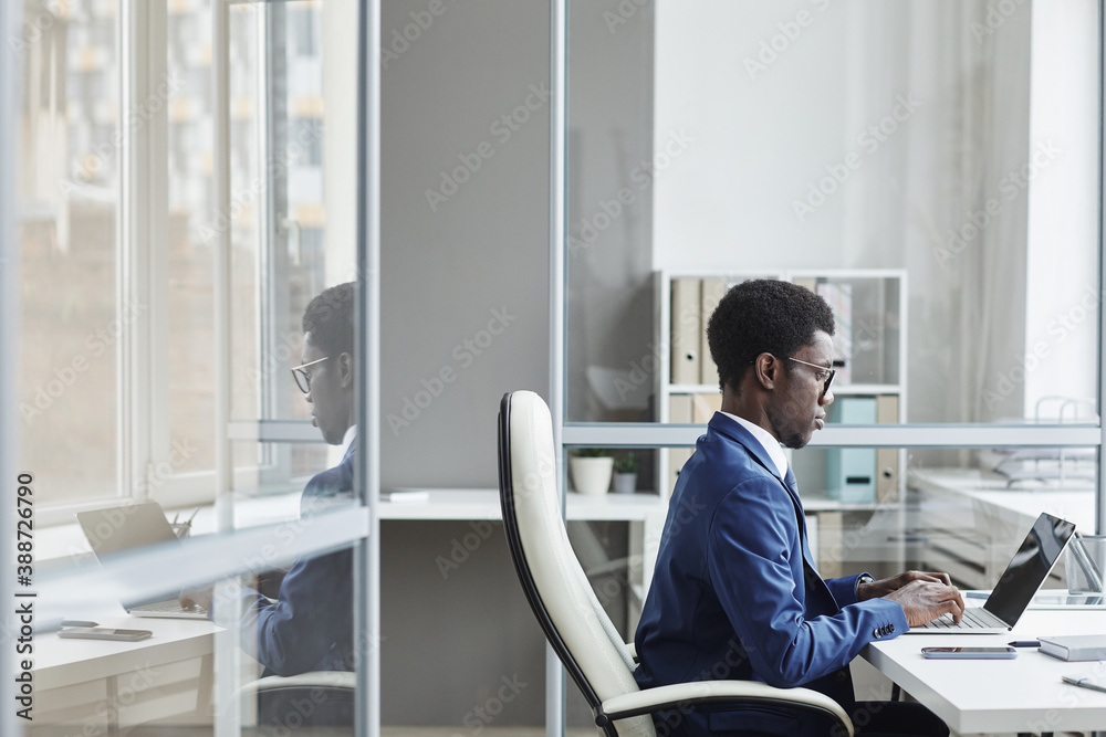 African businessman sitting at his workplace typing on laptop he working online at office - obrazy, fototapety, plakaty 