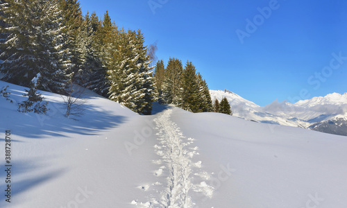 footprint in the fresh snow crossing snowcapped mountain under blue sky