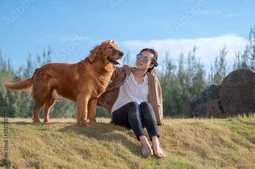 Golden retriever sits on the grass with the owner