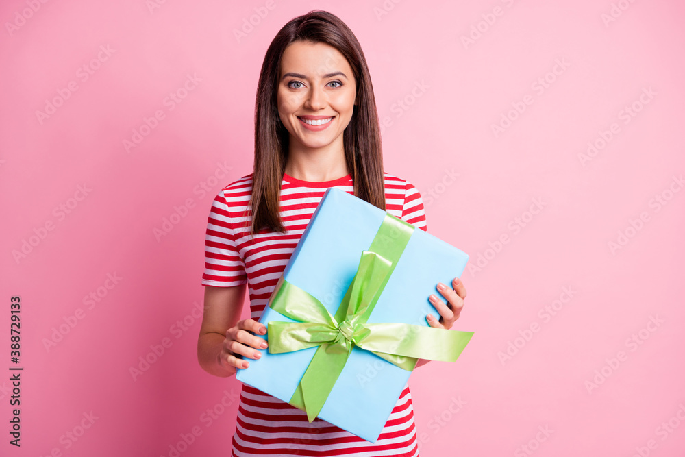 Photo of pretty happy attractive girl hold gift wear striped red white t-shirt isolated on pink color background Photo of pretty happy attractive girl hold gift wear striped red white t-shirt isolated on pink color background