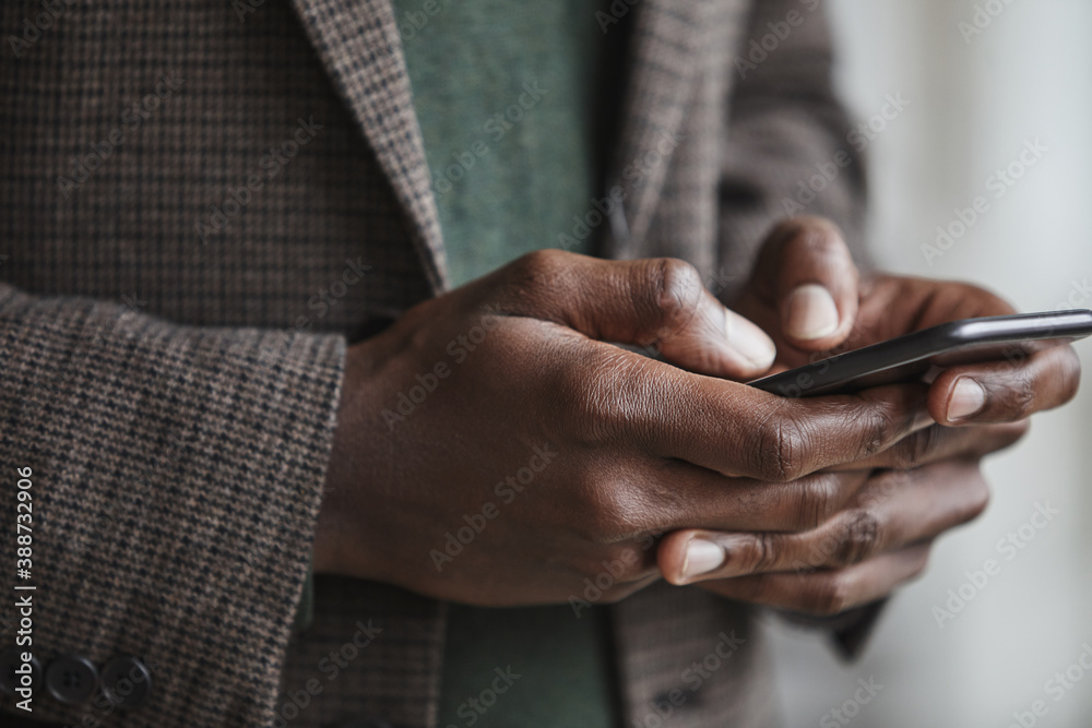 Close-up of African businessman in suit typing a message on his mobile phone
