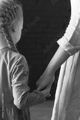 Mom's hug. Daughter and mom are standing and mom holds her daughter's hands tightly in her arms. Childhood and motherhood. A daughter in an orange linen dress with mother. Mom's hand. 