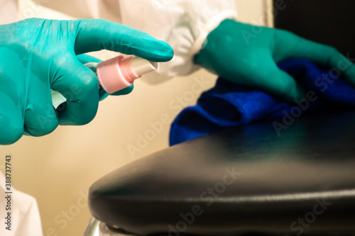 The hand of the person wearing blue gloves Hold a spray of alcohol Spraying disinfection on the seat The other hand holds the cloth for wiping the concept covid-19.2/