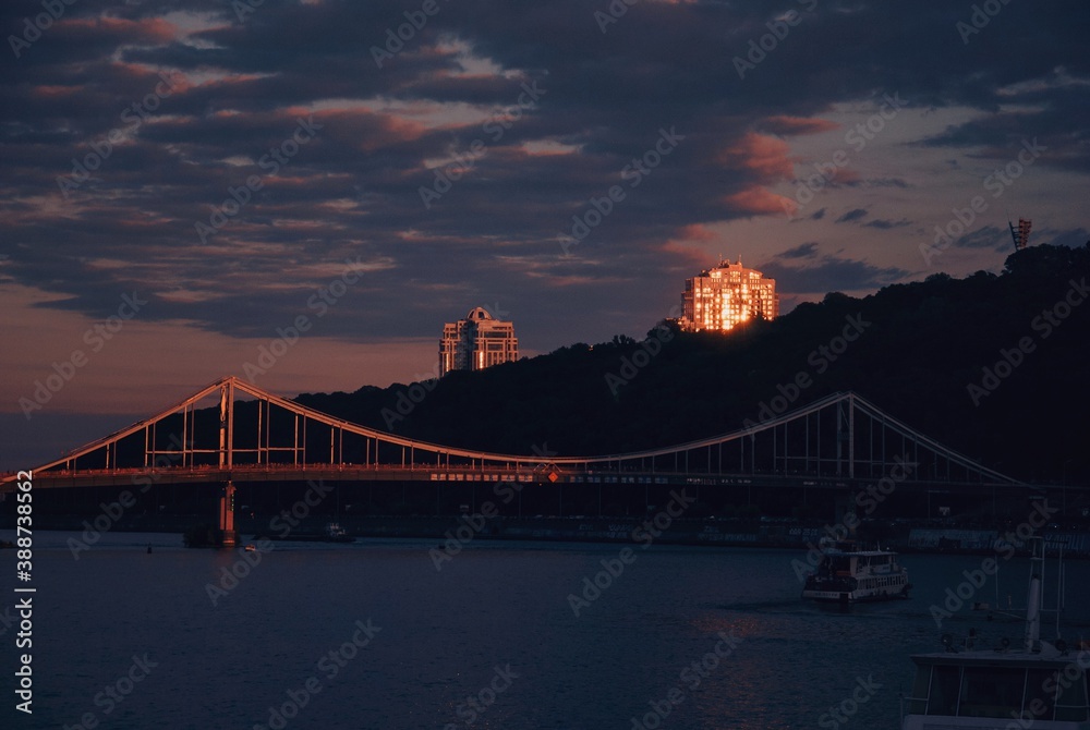 Evening sky, pink sky and dark blue clouds, buildings, bridge and trees, urban aesthetics, river