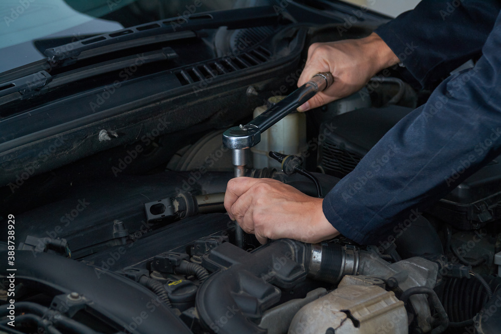 Man tightens spark plug with torque wrench