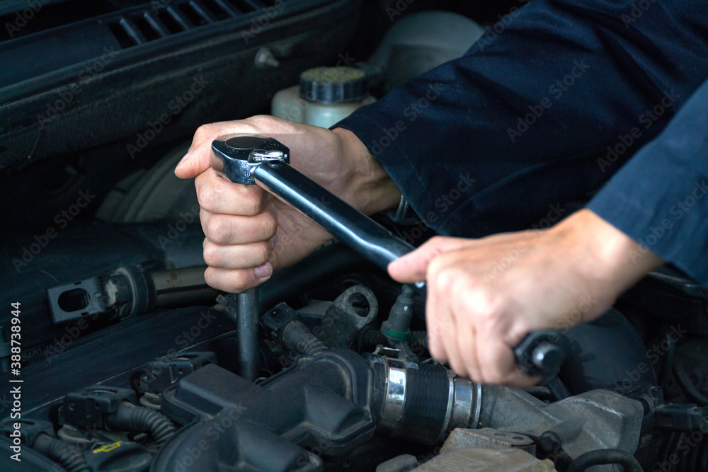 Man tightens spark plug with torque wrench Man tightens spark plug with torque wrench