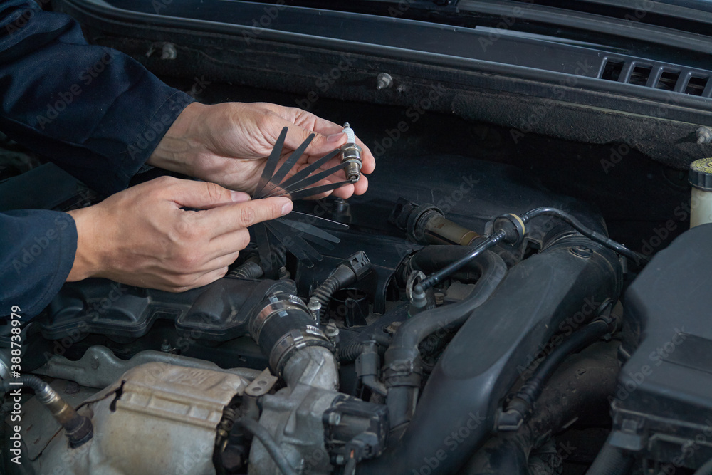 A man checks the spark gap in the spark plug with a probe, close-up A man checks the spark gap in the spark plug with a probe, close-up
