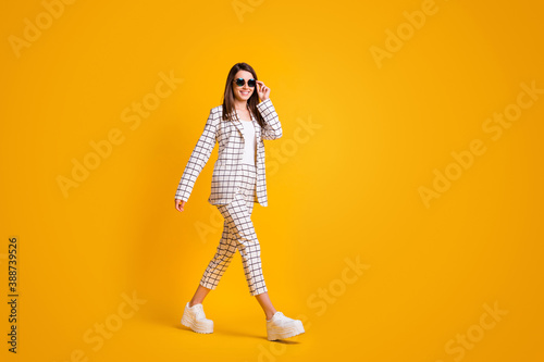 Full length body size side profile photo of girl touching sunglass walking fast isolated on vibrant color background with blank space