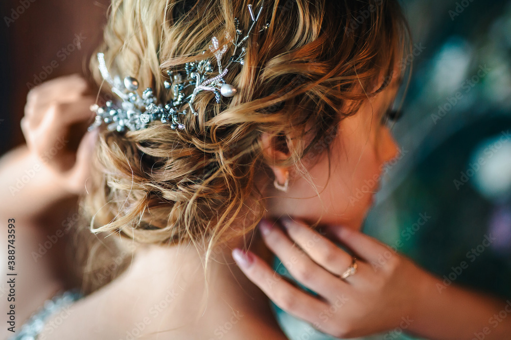Bride in a dress with an open back. Hairstyle with beads and wire decoration. Copper and brown hair color. Selected focus. Blurred background