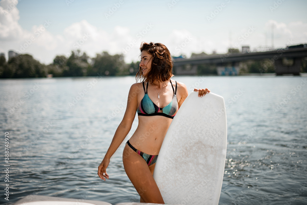 view of beautiful young woman in bright bikini with surf board with her hands view of beautiful young woman in bright bikini with surf board with her hands