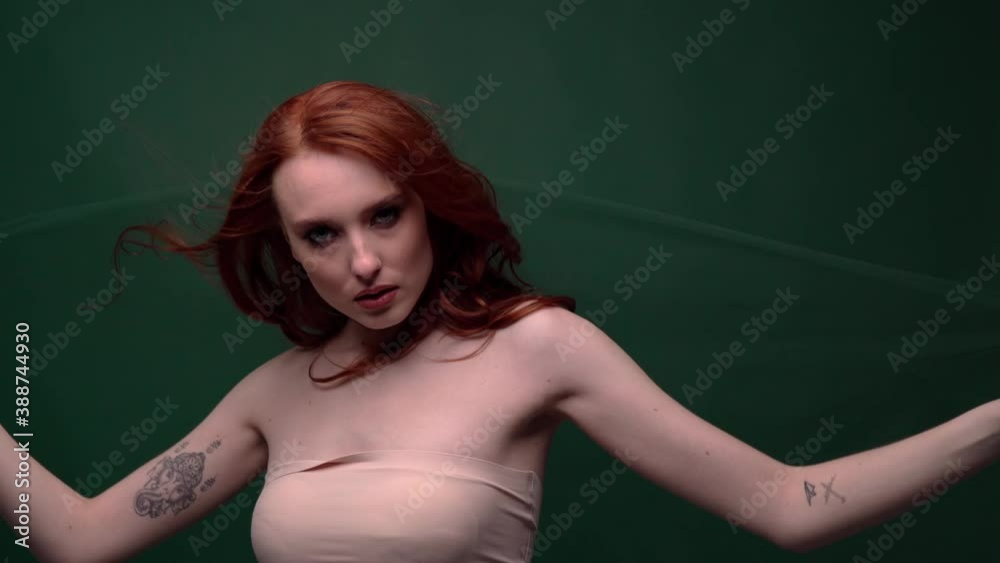 Beautiful fashionable girl with long curly red hair. Girl in the studio on a blue background. Advertising, hair products, beauty salon, cosmetics, clothing. Fashion, boutique. Beautiful fashionable girl with long curly red hair. Girl in the studio on a blue background. Advertising, hair products, beauty salon, cosmetics, clothing. Fashion, boutique.
