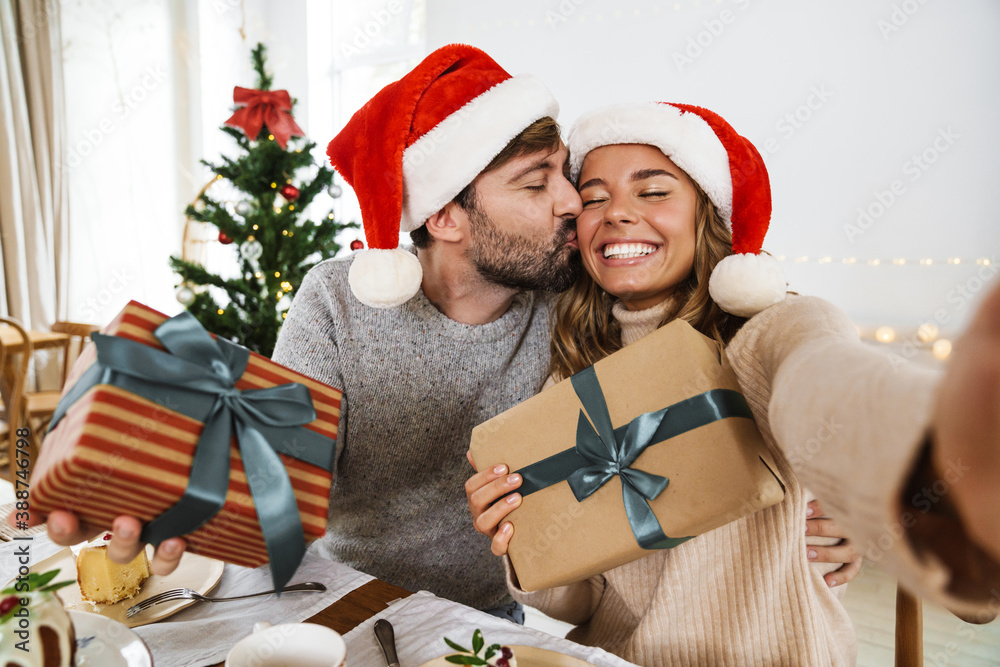 Fototapeta premium Nice excited couple taking selfie while having Christmas dinner