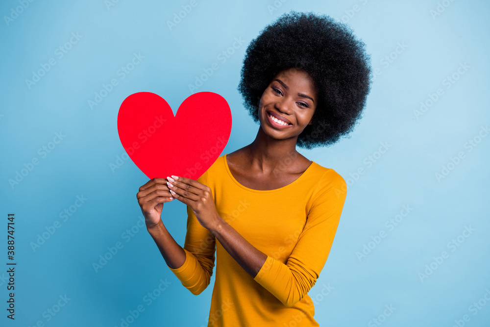 Photo portrait of happy smiling black skinned girl showing red paper symbol of valentines day heart isolated on bright blue color background Photo portrait of happy smiling black skinned girl showing red paper symbol of valentines day heart isolated on bright blue color background