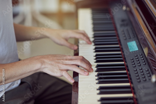 Hands of white shirt pianist playing on piano keyboard.