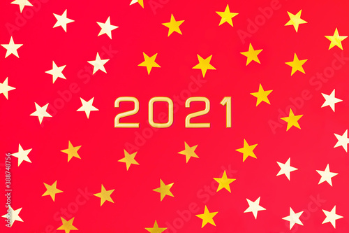 Numbers 2021 among gold yellow and white five-pointed stars on a red background. New Year postcard. Flatly, top view