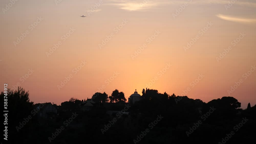 Wide view of an aircraft approaching Dubrovnik airport at sunset, over the Racic Mausoleum, in Cavtat, Croatia beneath a glorious golden sunset sky. Wide view of an aircraft approaching Dubrovnik airport at sunset, over the Racic Mausoleum, in Cavtat, Croatia beneath a glorious golden sunset sky.