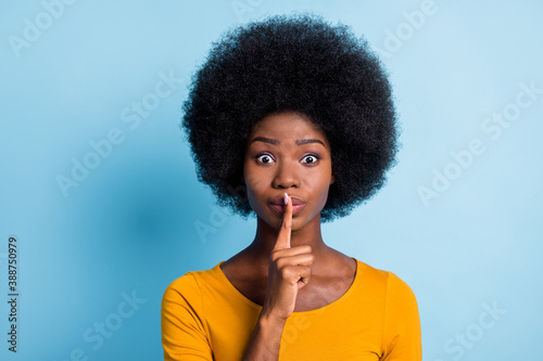 Photo portrait of black skinned girl keeping finger near lips speechless quietly isolated on vibrant blue color background