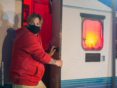 Hombre entrando en su autocaravana durante la noche de halloween, usando mascarilla para protegerse de la pandemia del coronavirus