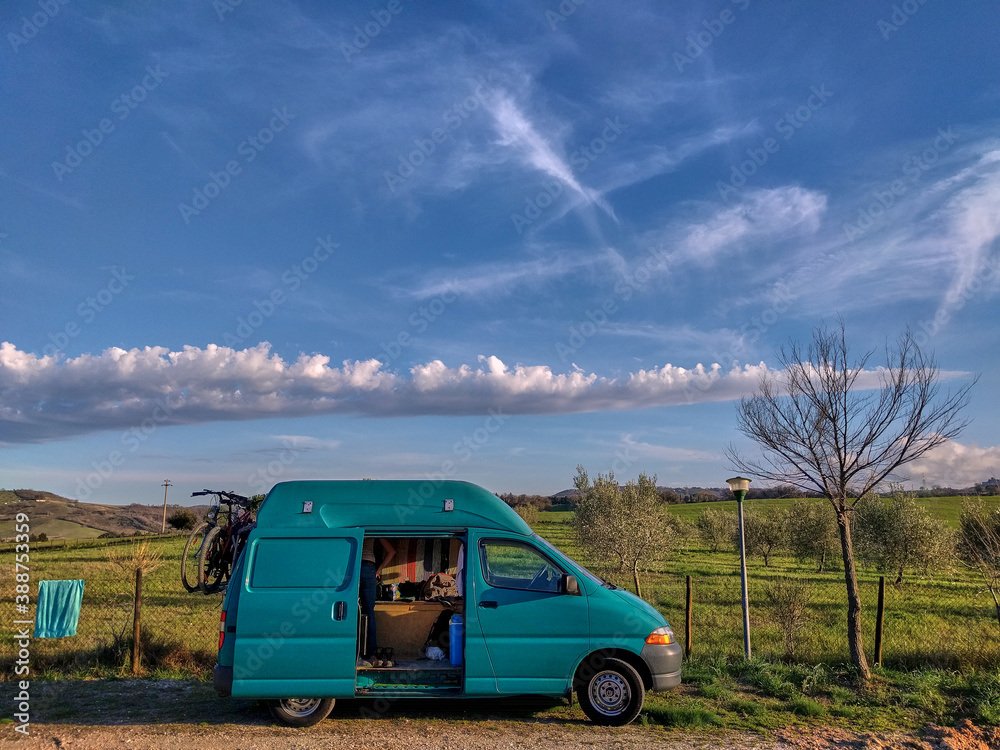 Campervan on a green field with blue sky. Green camper beneath blue sky ...
