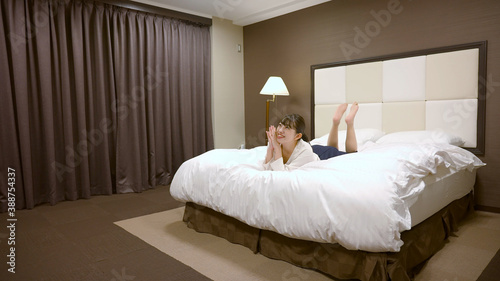 ホテルのベッドの上ではしゃいでいる女性