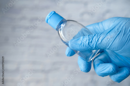  hand in protective gloves holding sanitizer gel 