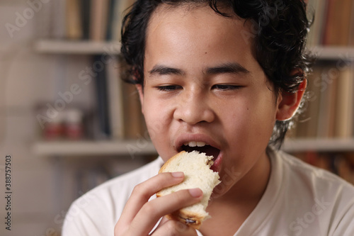 Asian boy eating bread with chocolate cream  student enjoys breakfast or snacks of toast with jam