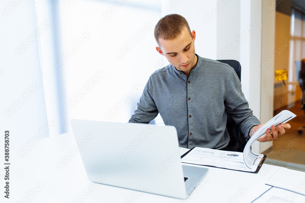 Young business man working on laptop while sitting at work table in working office