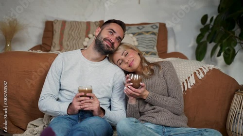 Lovely wife rest head on man shoulder. Romantic couple have a cup of hot chocolate sitting on the floor of the bedroom on a winter day.
