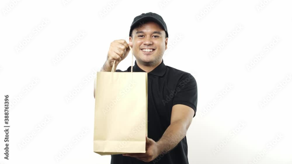 Asian delivery man in black uniform holding the paper bag giving to customer on isolated white background. 4k Resolution. Asian delivery man in black uniform holding the paper bag giving to customer on isolated white background. 4k Resolution.