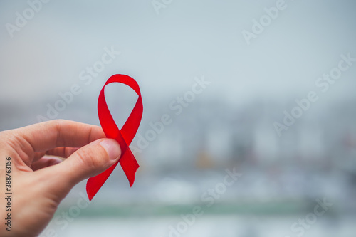 Red bow ribbon symbol HIV, AIDS cancer awareness with shadows, studio shot isolated on red background, Healthcare medicine concept, World AIDS Day