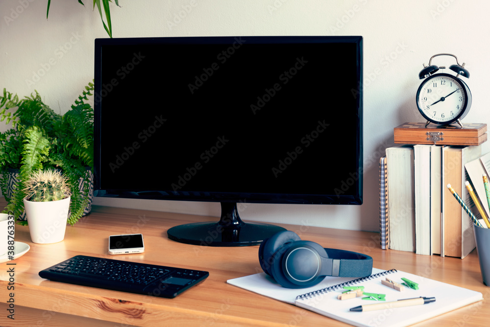 Wooden office desk with monitor with blank screen, book, pen, cans, keyboard and clock. Workplace during home office with design table and business online. Wooden office desk with monitor with blank screen, book, pen, cans, keyboard and clock. Workplace during home office with design table and business online.