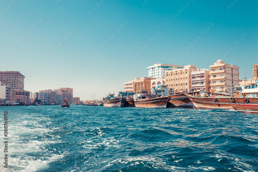 Skyline view of Dubai Creek with traditional boats and piers. Sunny summer day. Famous tourist destination in UAE.