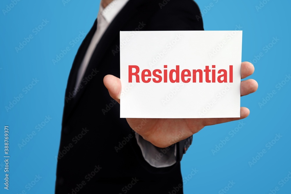 Residential. Businessman in suit showing business card with text. Man isolated on blue background Residential. Businessman in suit showing business card with text. Man isolated on blue background